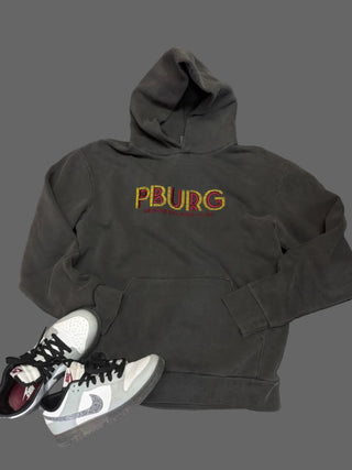 Dark gray hoodie with 'PBURG' text and a white sneaker on a dark surface